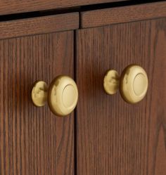 two brass knobs on the side of a wooden cabinet