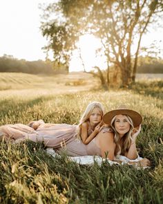 two women are laying in the grass together