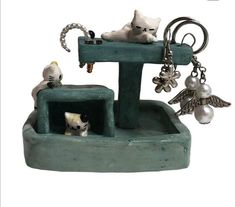 a cat figurine sitting on top of a fountain with key chains hanging from it's sides