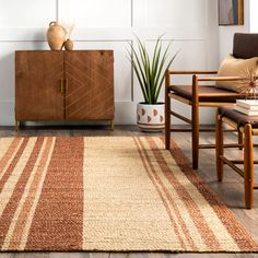 a living room area with a rug, chair and sideboard in the corner next to a potted plant