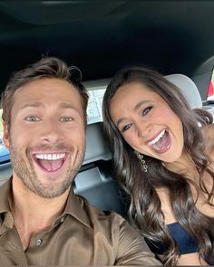 a man and woman sitting in the back seat of a car