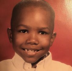 a young boy in a white shirt and tie smiling at the camera with red background