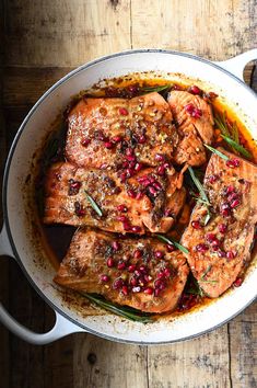 a pan filled with meat covered in pomegranates and garnishes