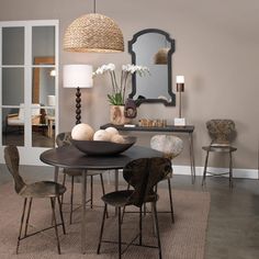 a dining room table with chairs and a bowl of eggs on it in front of a mirror