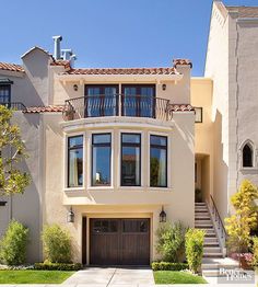 a large beige house with lots of windows on the top floor and stairs leading up to it