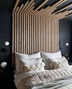 a large bed sitting under a wooden headboard next to a wall with lights on it