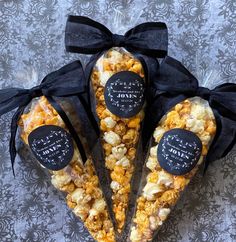 three bags filled with popcorn sitting on top of a table next to black ribbon bows