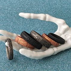 four different colored rings sitting on top of a white plastic holder with two black and one brown ring