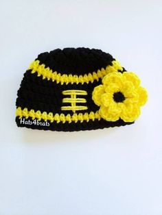 a crocheted football hat with a flower on the front and black, yellow and white stripes