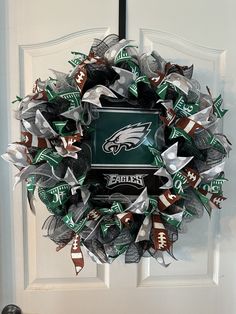 a wreath with the philadelphia eagles on it hanging in front of a door decorated with footballs