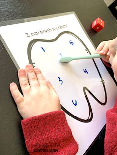 a young child using a toothbrush to write numbers