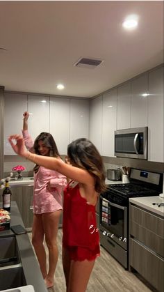 two young women are dancing in the kitchen