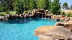 an outdoor pool with waterfall and rocks