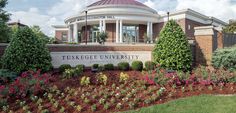 the tuskegee university campus sign is surrounded by flowers and bushes in front of it