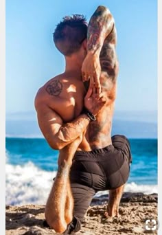 a man doing yoga on the beach with his back to the camera and hands behind him