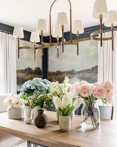 vases filled with flowers sit on a wooden table