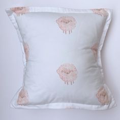 a white pillow with pink sheep on it