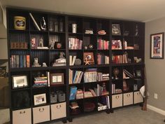 a bookshelf filled with lots of books next to a wall full of pictures