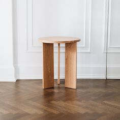 a wooden table sitting on top of a hard wood floor next to a white wall