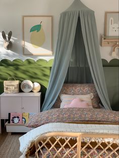 a bed with a canopy over it sitting in a bedroom next to a dresser and pictures on the wall