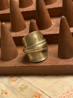 a ring is sitting on top of a wooden board with cones in the back ground