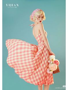 a woman in a pink and white checkered dress holding a basket full of flowers