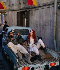 two people sitting in the back of a pick up truck