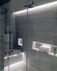 a bathroom with a glass shower door and white towels on the shelf next to it