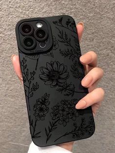 a woman holding up her phone case with flowers on the front and back cover in black