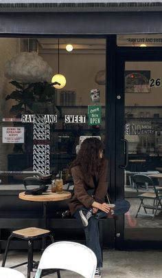 a woman sitting at a table in front of a store