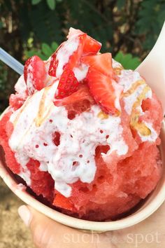 a bowl filled with ice cream covered in strawberries and other toppings on top of it