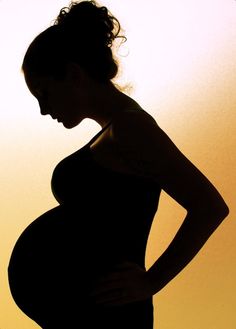 a pregnant woman is silhouetted against an orange and yellow background with her hands on her hips