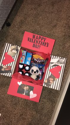 an open valentine's day box sitting on the floor with pictures and candies