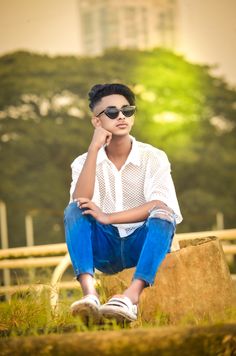 a young man sitting on top of a rock