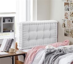 a bed with a white headboard sitting next to a desk and bookshelf