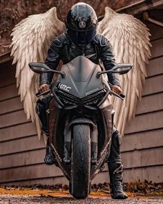 a man riding on the back of a motorcycle with angel wings around his head and helmet