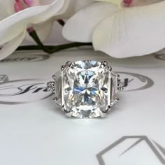 a diamond ring sitting on top of a table next to some flowers and white orchids