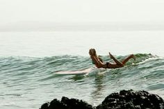 a woman laying on a surfboard in the ocean