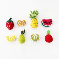 small felt fruits are arranged on a white surface