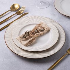 a white plate topped with a piece of cake next to silverware and gold forks