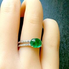 a person's hand with a ring on it and a green stone in the middle