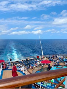 the deck of a cruise ship with people sitting on lounge chairs and umbrellas in the water