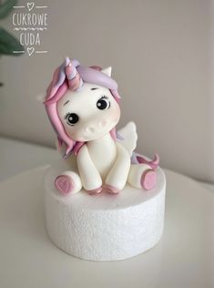 there is a small white cake with a pink pony sitting on it's side