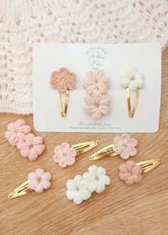 the hair clips are decorated with crochet flowers and gold bobby pins on a wooden surface