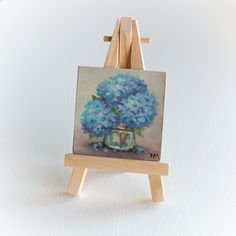 a small easel with a painting of blue flowers on it