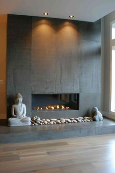 a modern fireplace in the middle of a living room with two buddha statues on each side