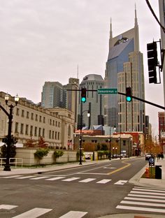 an intersection with traffic lights and tall buildings in the background, including one green light