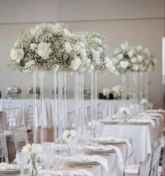 the tables are set with white flowers and silverware for an elegant wedding or reception