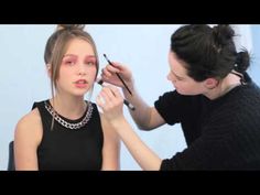 a woman is getting her make up done by another woman who is wearing a black top