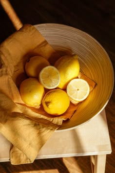 a bowl filled with lemons on top of a wooden table